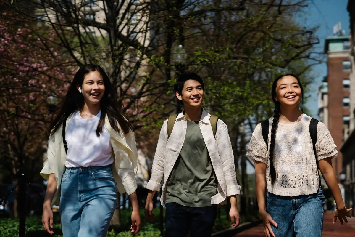 Three friends walking together outdoors, smiling.