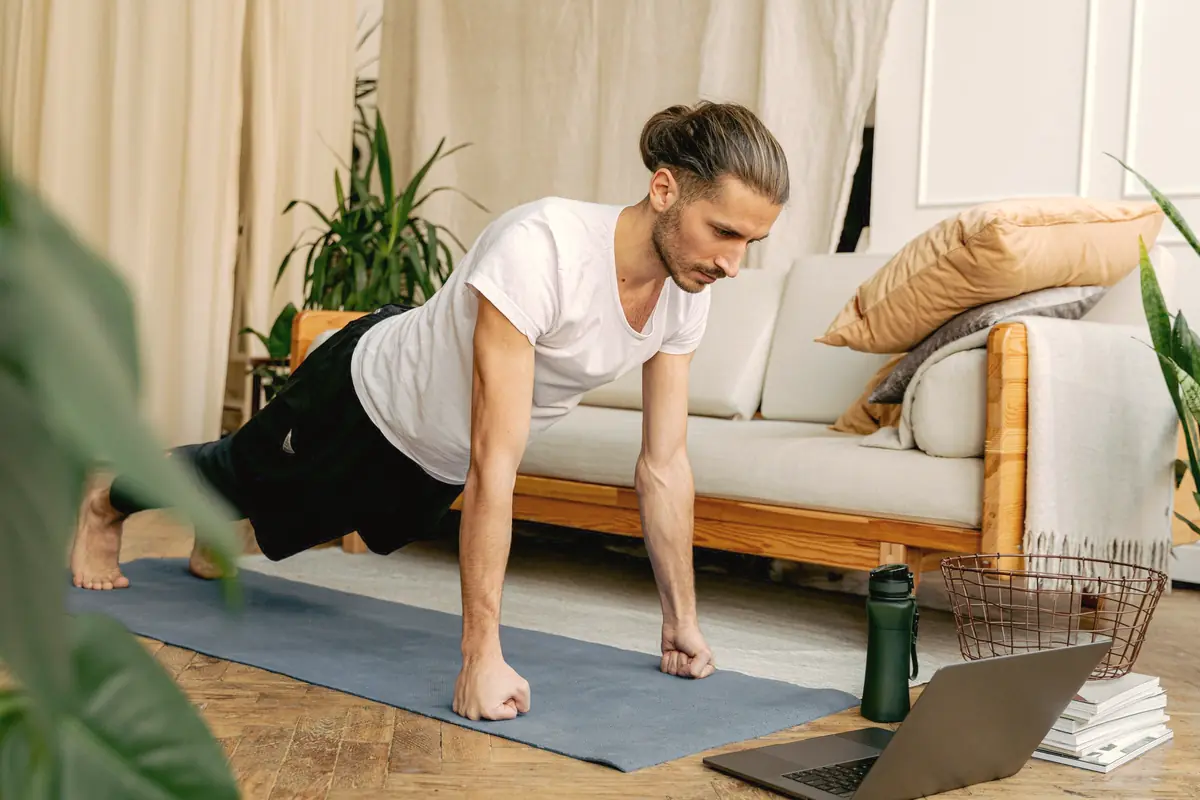 A man doing a push-up on a mat in his living room.